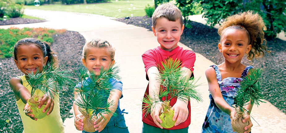 Kids showing trees they will plant in a Michigan park